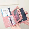 A pink passport wallet with RFID protection features and multiple card slots is being held by a hand.