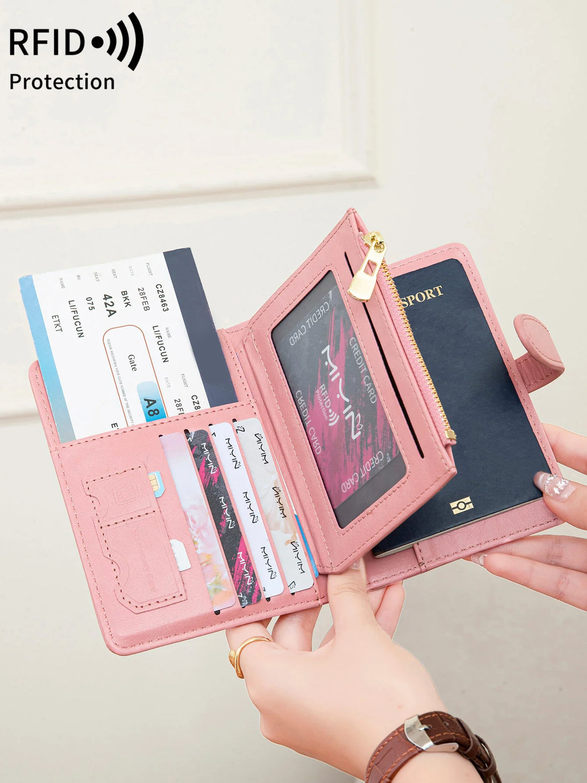 A pink passport wallet with RFID protection features and multiple card slots is being held by a hand.