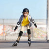 A young boy wearing a yellow shirt and protective gear is skating on a dark surface.