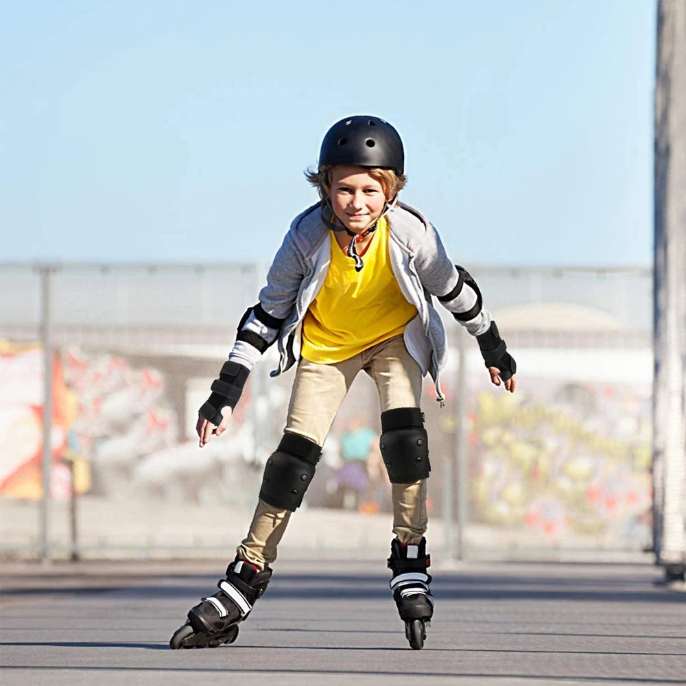 A young boy wearing a yellow shirt and protective gear is skating on a dark surface.