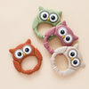Three silicone owl-shaped teethers and rattles in green, pink, and beige tones
