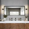 A modern bathroom vanity featuring a large mirror, stone countertop, and black wall sconces above wooden cabinetry.