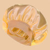 A light peach satin wide brim shower cap folded and displayed against a neutral background.
