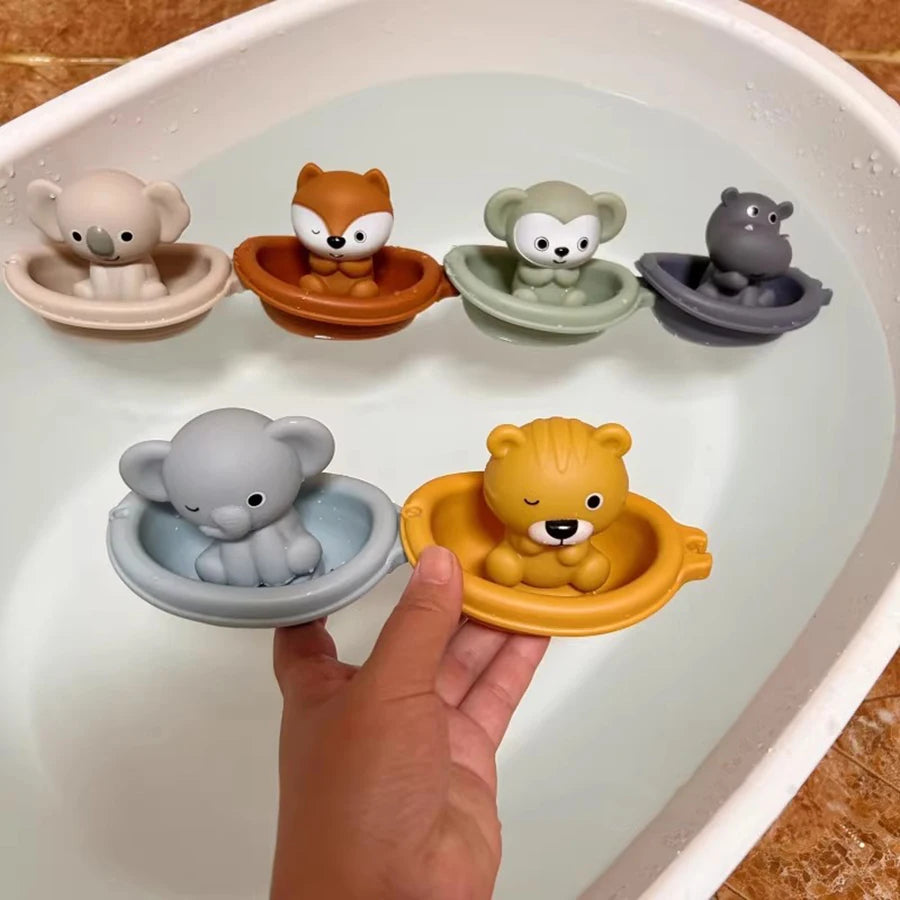 A hand is placing a silicone animal finger puppet bath toy into a white bowl filled with other silicone animal toys.