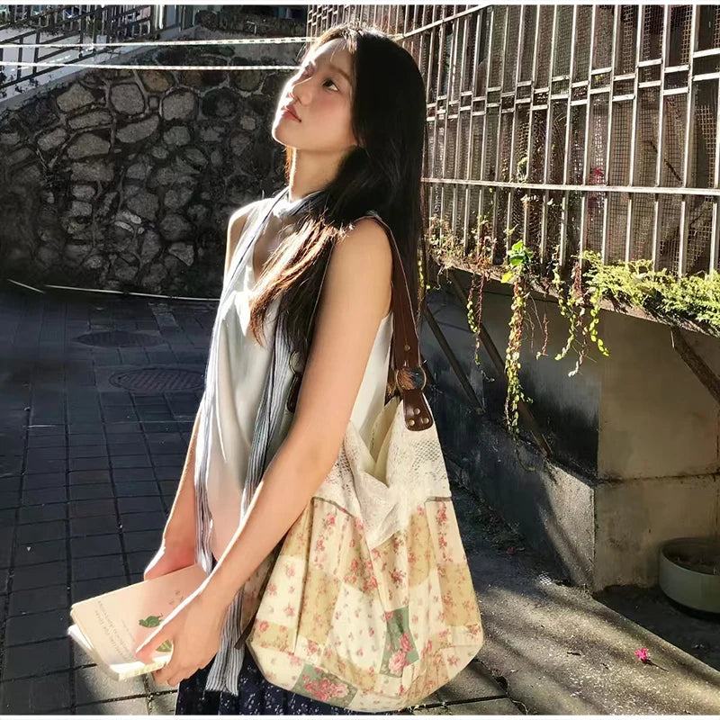 Une femme portant un haut blanc et une jupe foncée tient un sac à épaule patchwork floral bohème à l'extérieur.