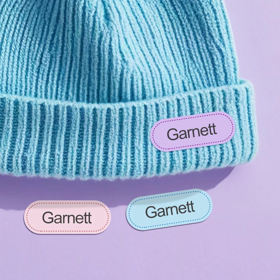 Gorro de punto azul claro con textura de ribete y dos etiquetas de nombre