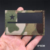 A rectangular tactical patch featuring a camouflage pattern with a black star and a dark rectangular insert on a hand.