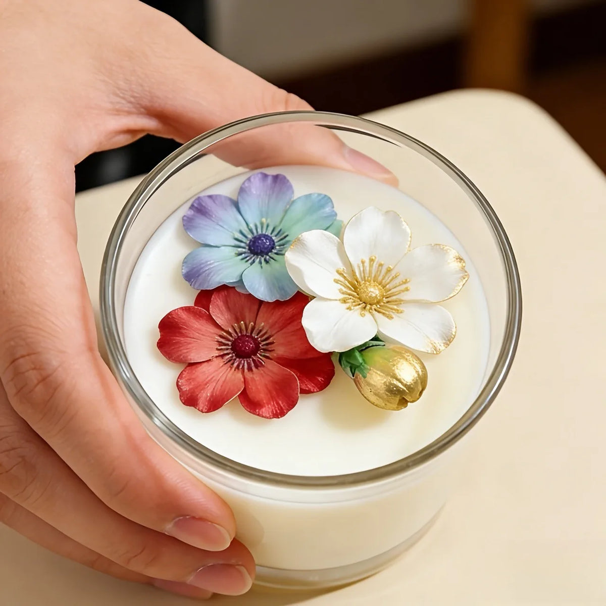 A hand holds a clear glass jar filled with white wax, featuring colorful lotus flower silicone molds for resin and craft proj