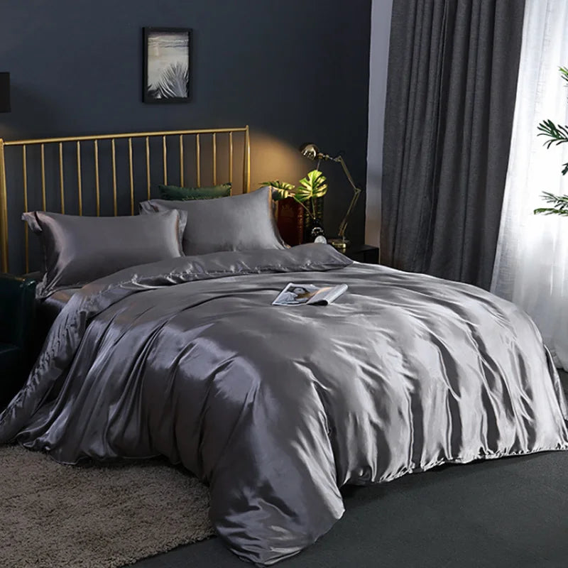 A luxurious gray silky duvet cover set displayed on a bed with a gold headboard and dark gray curtains.