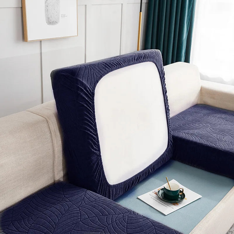 A dark blue stretch jacquard sofa cover with a white cushion and anti-slip backing on a light colored sofa.