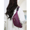 Un sac banane en nylon violet porté par une femme aux longs cheveux noirs, vu de dos.