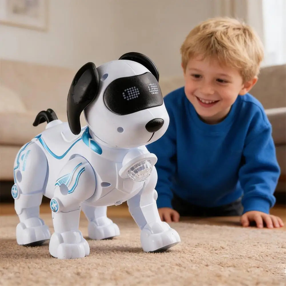 A smiling young boy is interacting with a white remote control robot dog toy on a carpet.