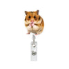 A cute brown hamster is attached to a silver badge reel with an alligator clip.