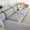 A gray jacquard elastic sofa slipcover with orange accent pillows on a light-colored sofa.