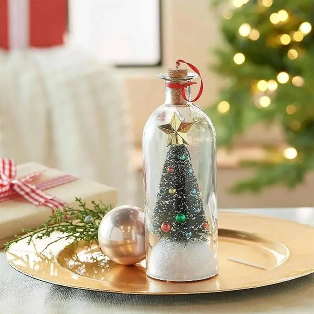 A glass bottle shaped like a Christmas tree with a snowy scene and a star topper sits on a gold plate.