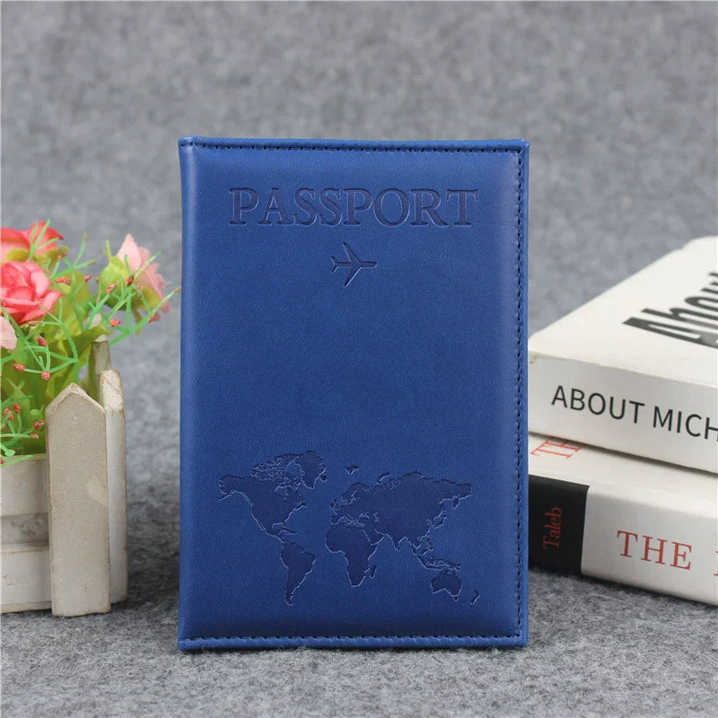 A dark blue leather passport holder featuring a world map design and card slots, resting on a gray surface.