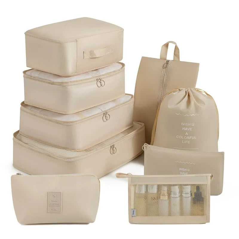 A set of beige travel packing cubes and storage organizer bags stacked and laid out.