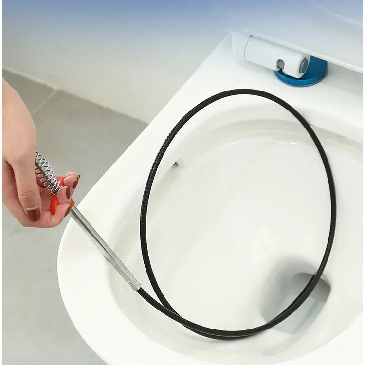 A hand is using a drain unclogging tool with an ergonomic handle to clear a drain in a toilet bowl.