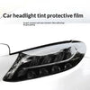 A close-up of a car headlight tinted with protective film, showing a dark, smoky finish.