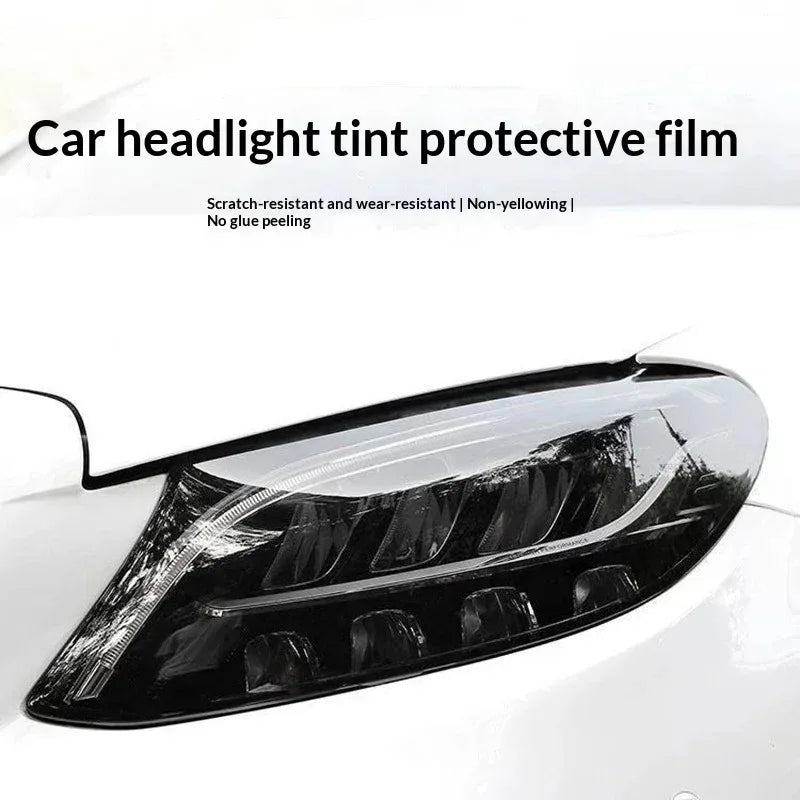 A close-up of a car headlight tinted with protective film, showing a dark, smoky finish.