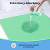 A hand pours water onto a green absorbent pad, demonstrating extra heavy absorbency and quick liquid locking.