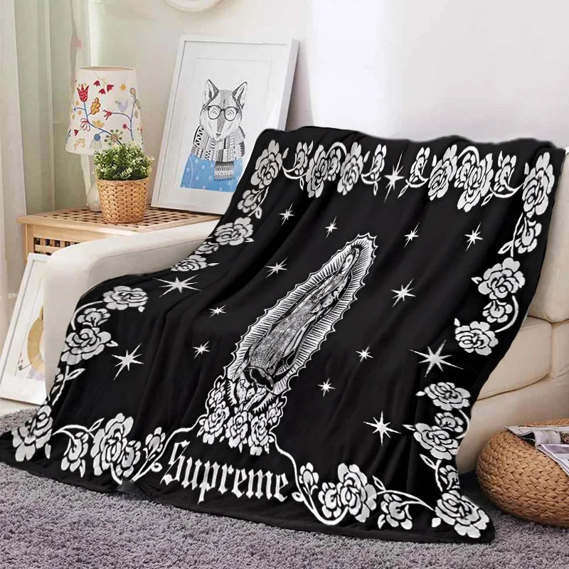 Black tapestry featuring a white floral design and the word Supreme on a sofa throw.