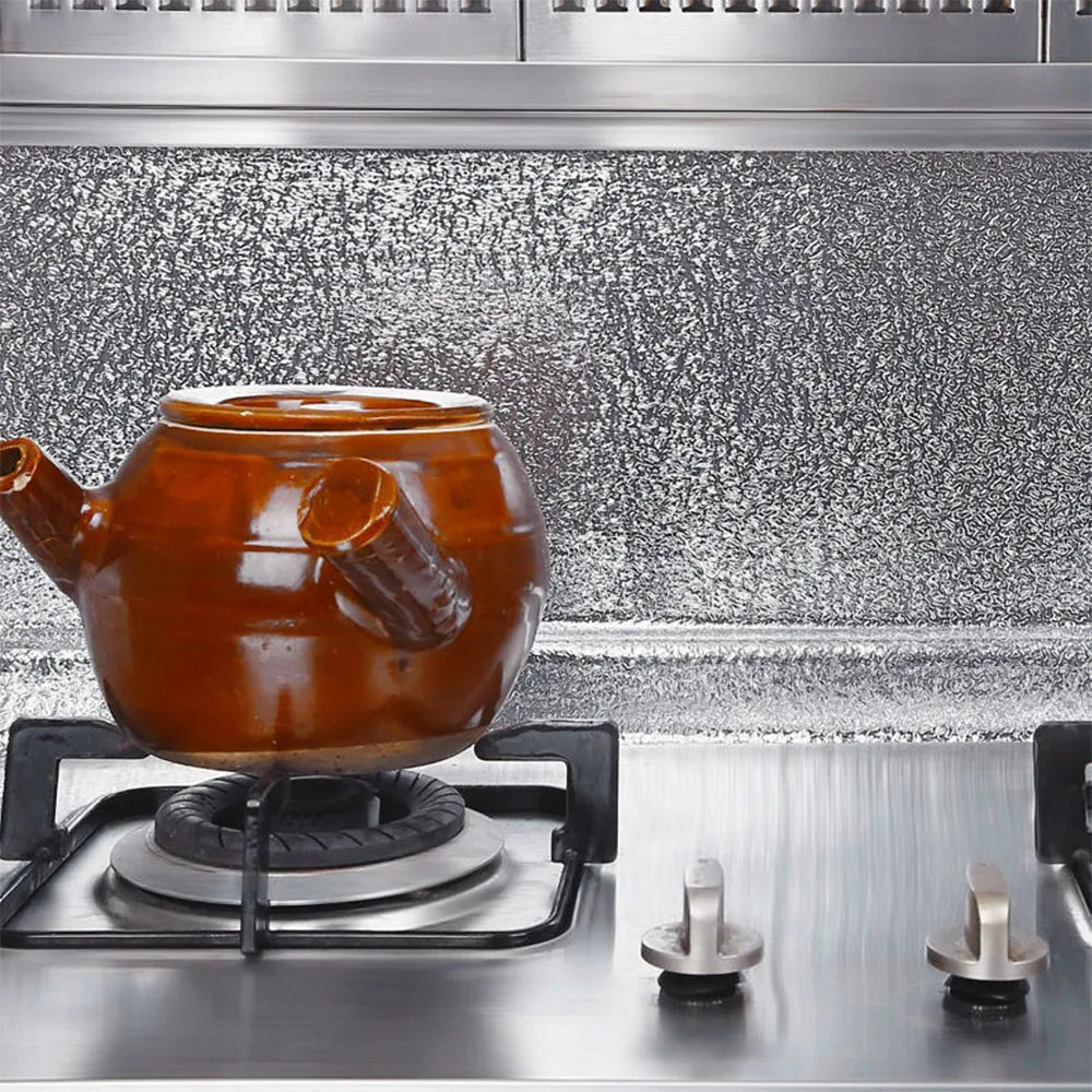 A brown ceramic teapot sits on a stovetop grate against a speckled metal kitchen backsplash.