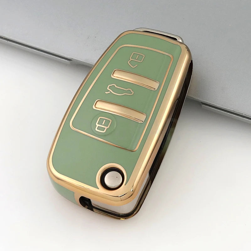 A close-up of a protective TPU key fob cover in a light olive green color with gold accents.