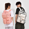 A person is holding a pink travel backpack with a laptop compartment against a white background.
