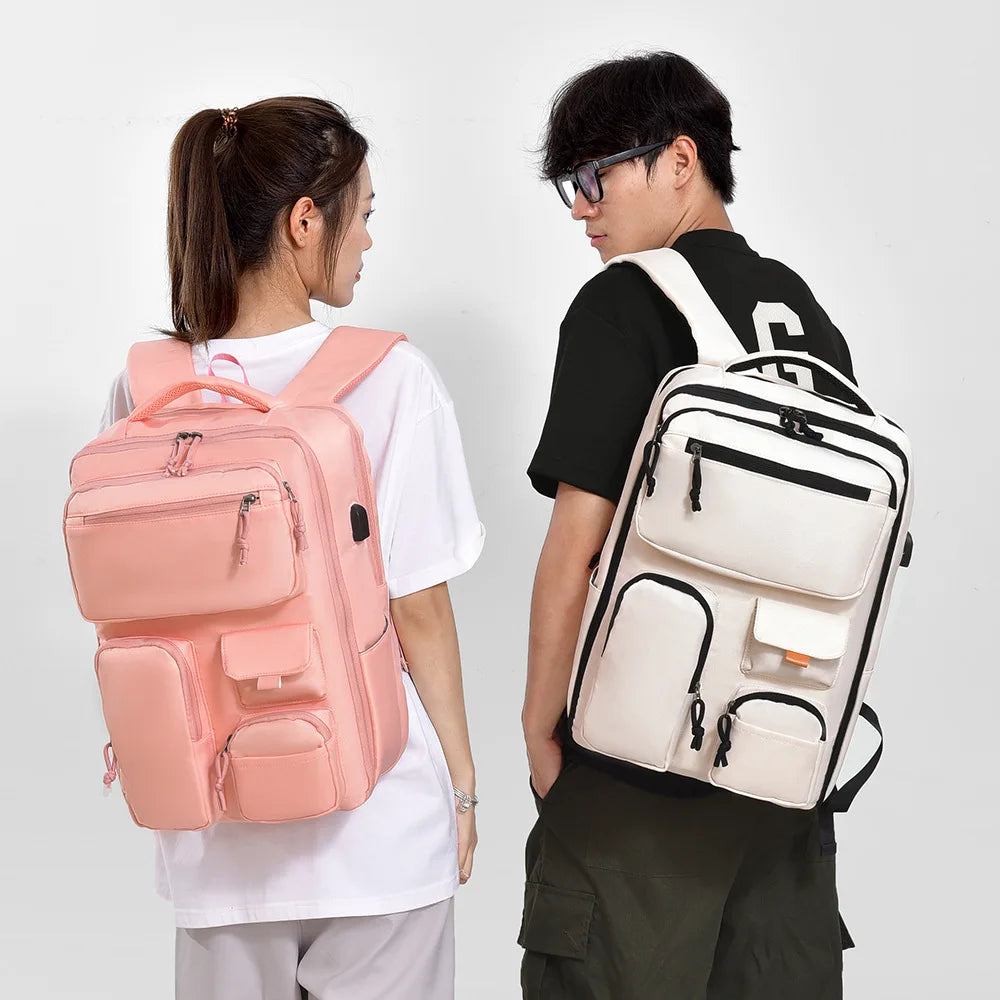 A person is holding a pink travel backpack with a laptop compartment against a white background.