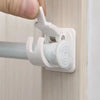 A hand is gripping a white adhesive curtain rod hook clamp attached to a wooden surface.