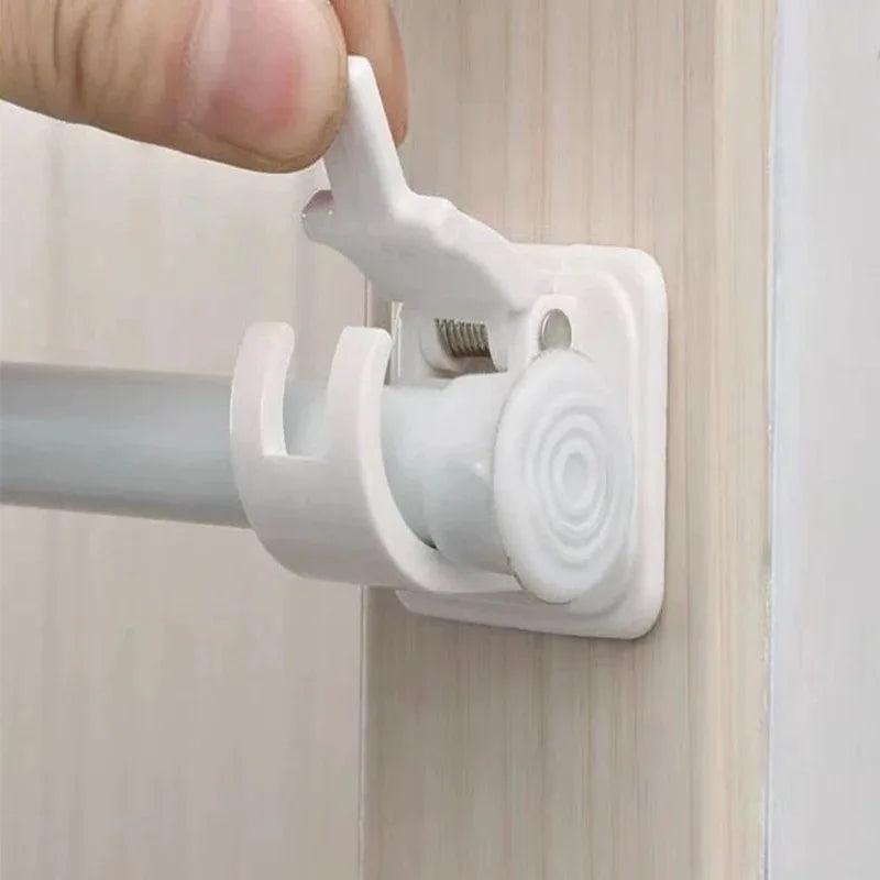 A hand is gripping a white adhesive curtain rod hook clamp attached to a wooden surface.
