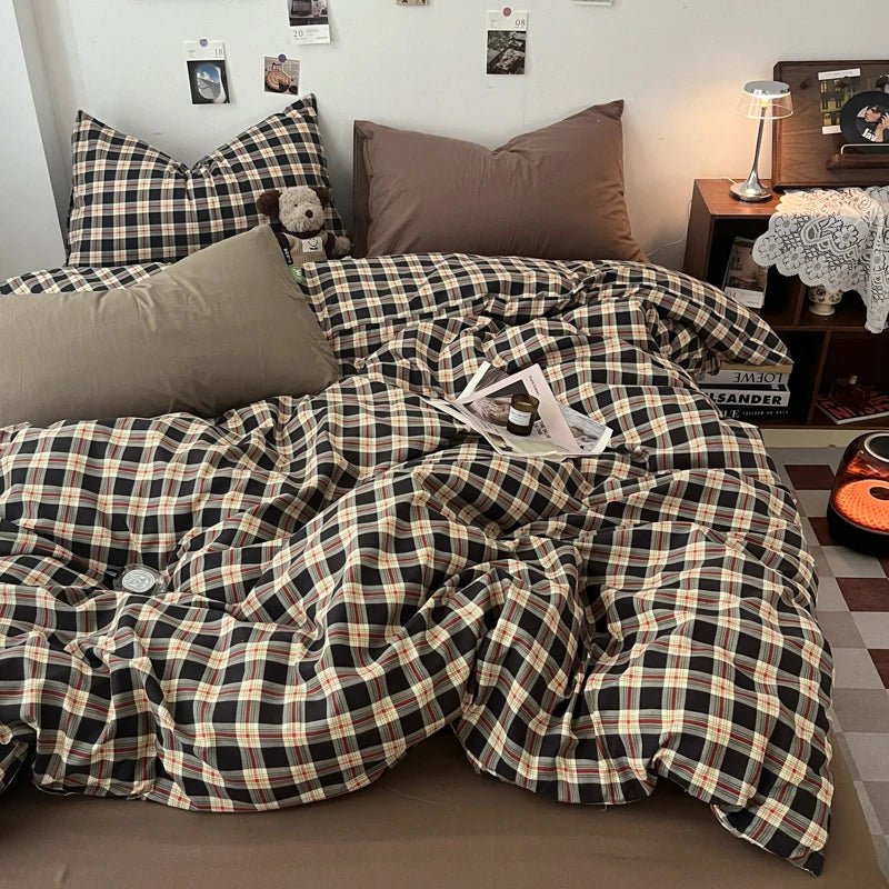 A plaid duvet cover set featuring black and tan checks is displayed on a bed with pillows.