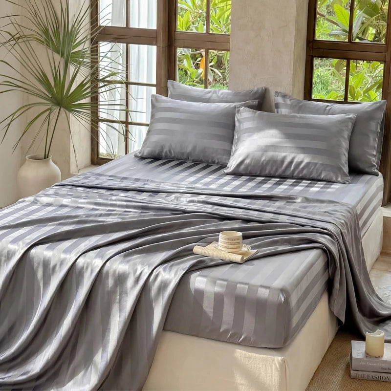 Gray striped satin bedding set displayed on a bed with natural light and greenery in the background.