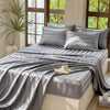 Gray striped satin bedding set displayed on a bed with natural light and greenery in the background.