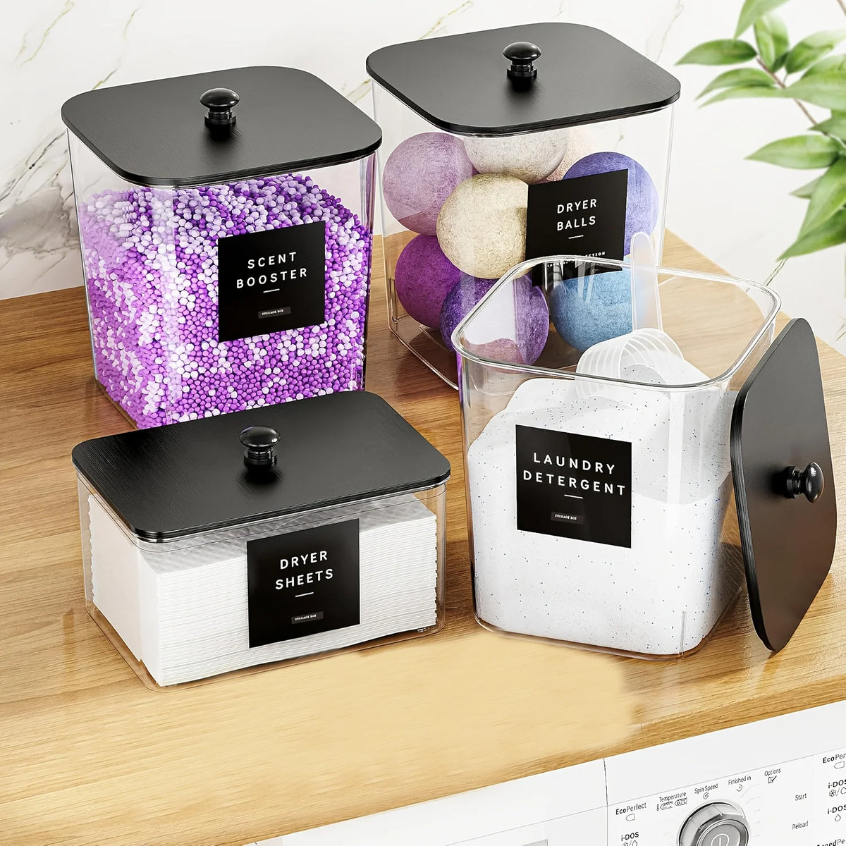 Three clear plastic storage containers with black lids hold laundry items like dryer balls and detergent sheets.