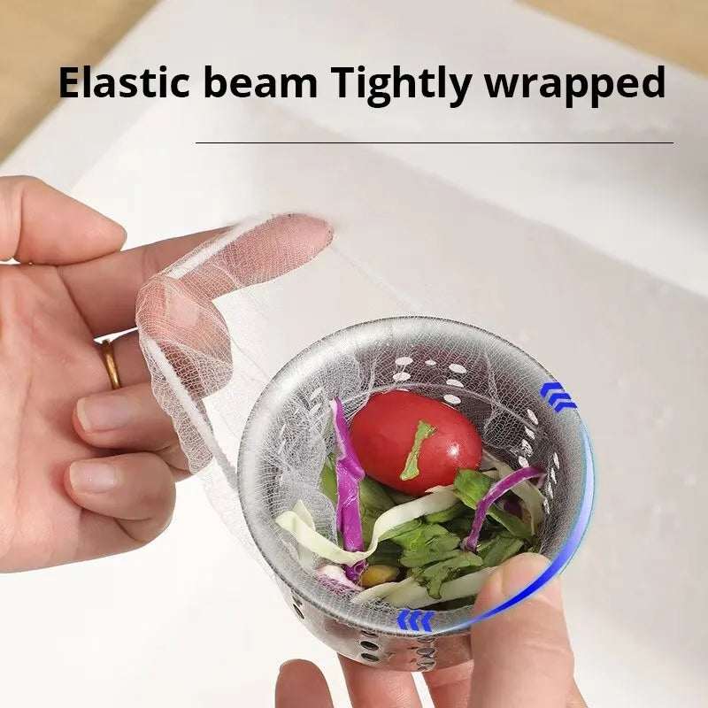A hand holds an elastic beam tightly wrapped disposable sink drain filter containing leafy greens and a tomato.