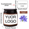 A brown glass jar candle with a white label featuring the text YOUR LOGO and a blue wind chime decoration.