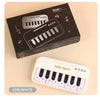 A white mini 15-key electronic keyboard piano is shown next to its packaging box.