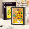 A framed sunflower painting featuring vibrant yellow and orange flowers, displayed next to its packaging.