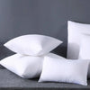 A stack of white square cushions on a gray surface.