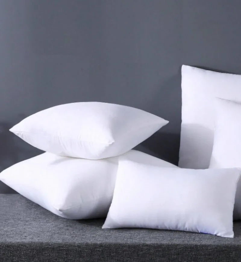A stack of white square cushions on a gray surface.