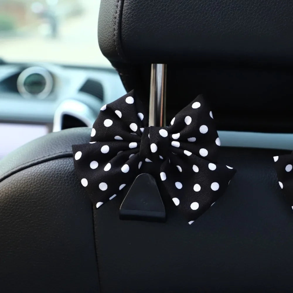 Black bow-shaped car seat back hook with storage attached to a black leather seat.