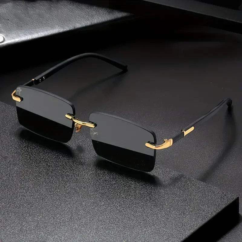 Lunettes de soleil rectangulaires sans monture noire avec accents dorés posées sur une surface sombre.