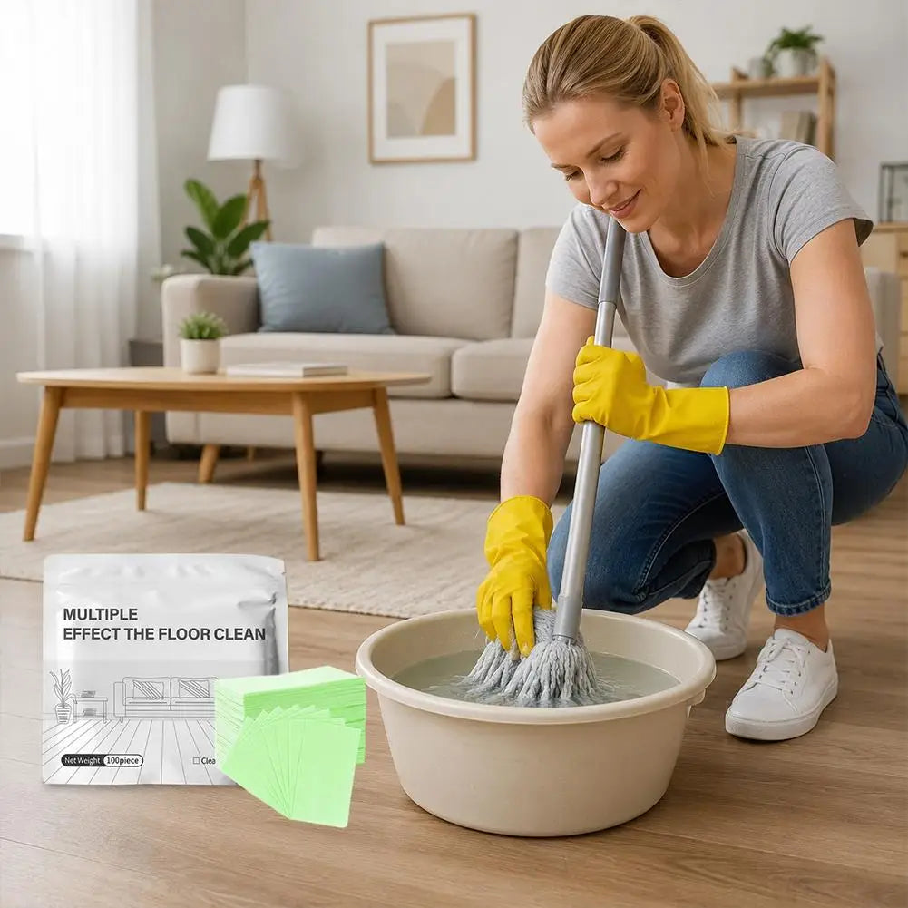A woman is mopping a floor with a cleaning tool and yellow gloves, with packaged floor cleaning tablets nearby.