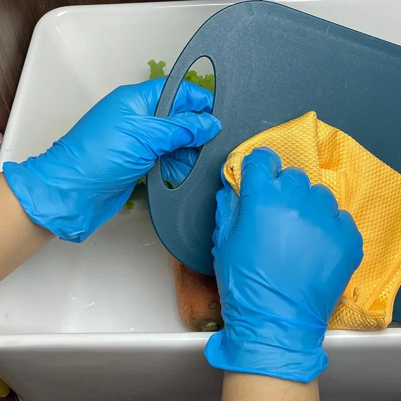 A hand wearing blue nitrile gloves is holding a dark gray plastic tool and an orange sponge in a white basin.