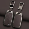 A pair of metallic key case covers with split rings and rectangular key holders resting on a dark surface.