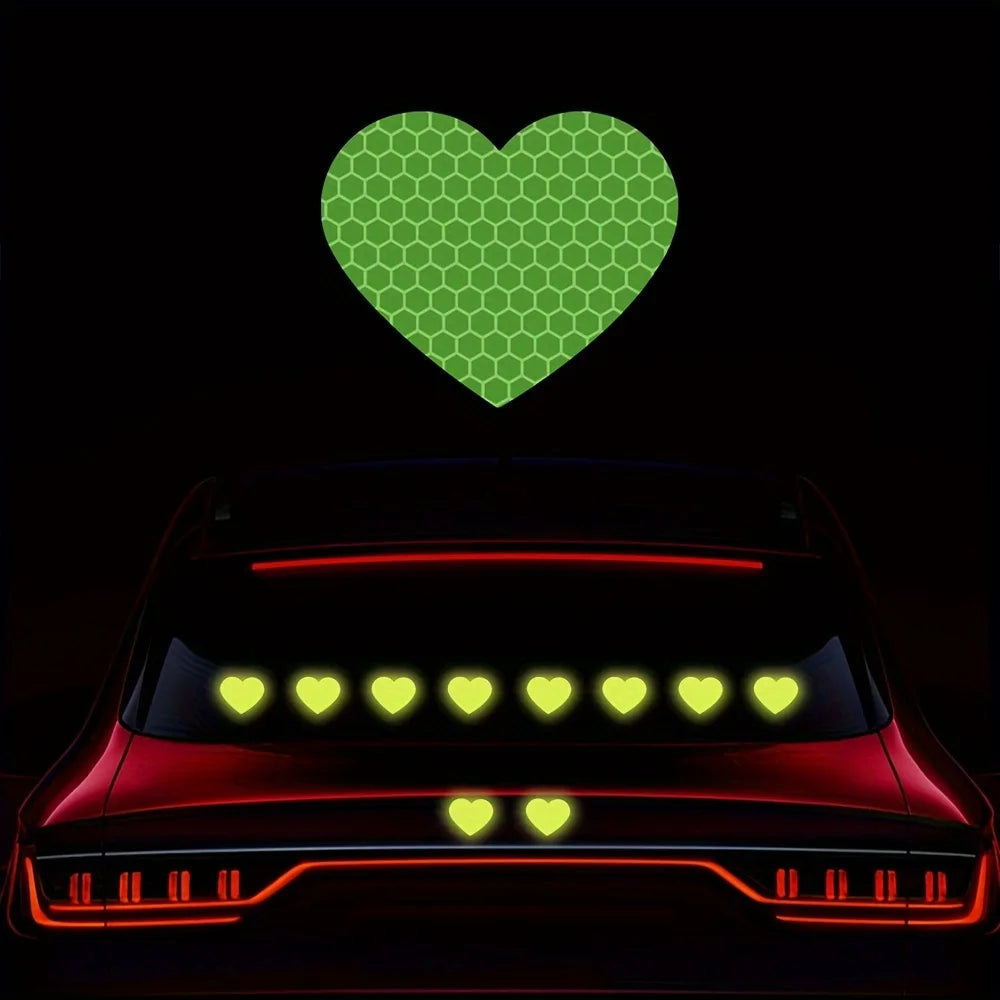 A red car with glowing yellow lights and a green heart sticker above it.