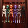 A row of colorful, poseable skull figures with skeletal details displayed on a wooden door.