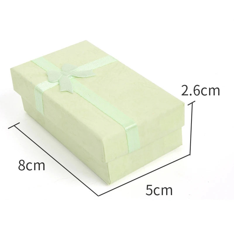 A rectangular light green velvet jewelry gift box tied with a pale green ribbon.